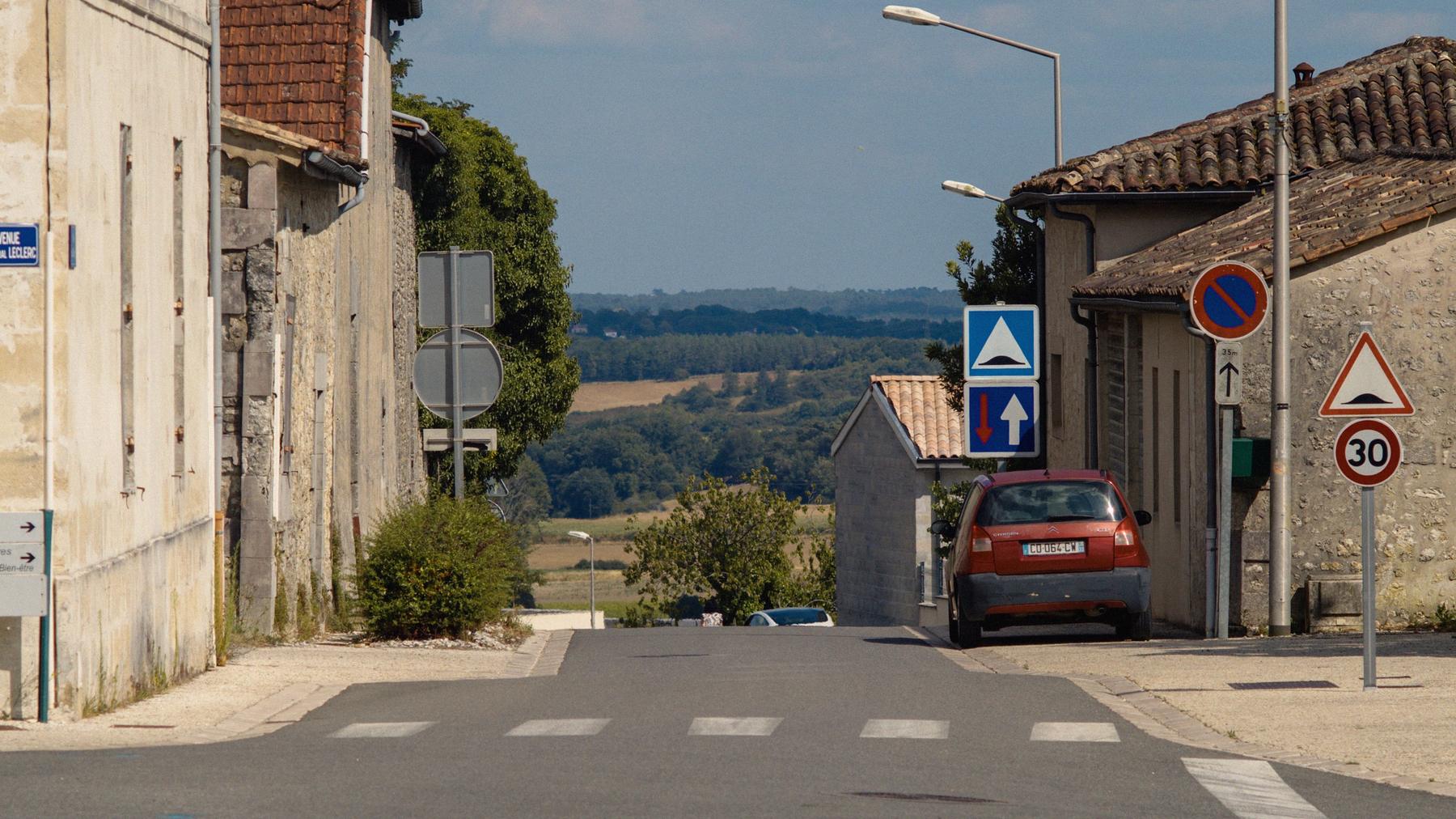Repérage de Pouet Pouet : un homme marche sur une petite route de campagne, au sommet d'une montée, entre un champ de maïs et les herbes sèches.