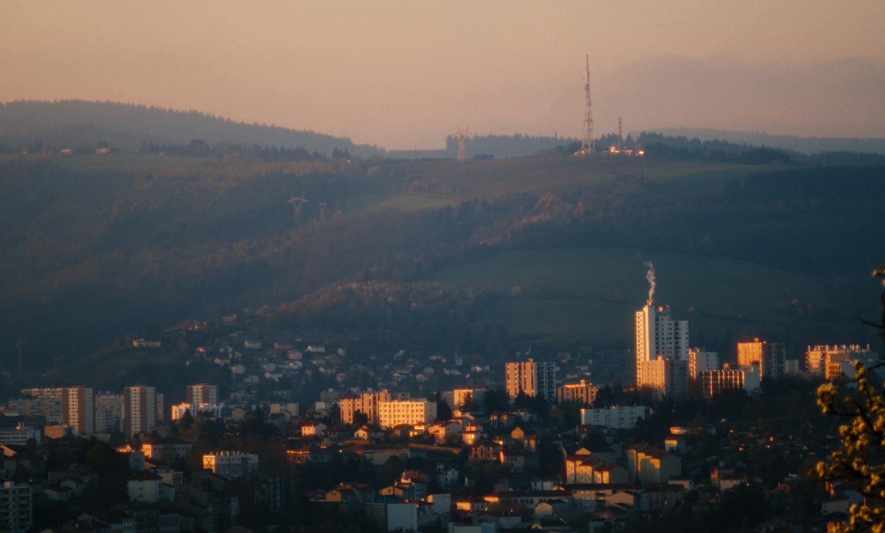Photogramme de Sainté : la ville de Saint-Étienne au soleil couchant, tours et collines dans une lumière dorée.
